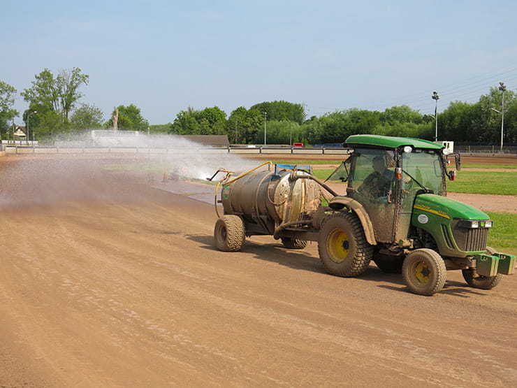 a tractor waters the circuit for sliding bikes on