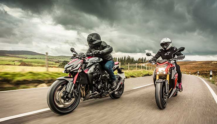 Two motorcyclists ride under dark clouds in the winter
