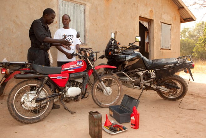 Sulayman Senghore,a Riders mechanic checks health worker Bubbacarr Jallow's motorcycle in The Gambia.