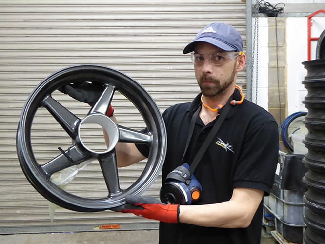 Machinist Chris Slade with a Dymag composite wheel. The construction is modular. Model specific hubs are bonded into place before final inspection takes place.